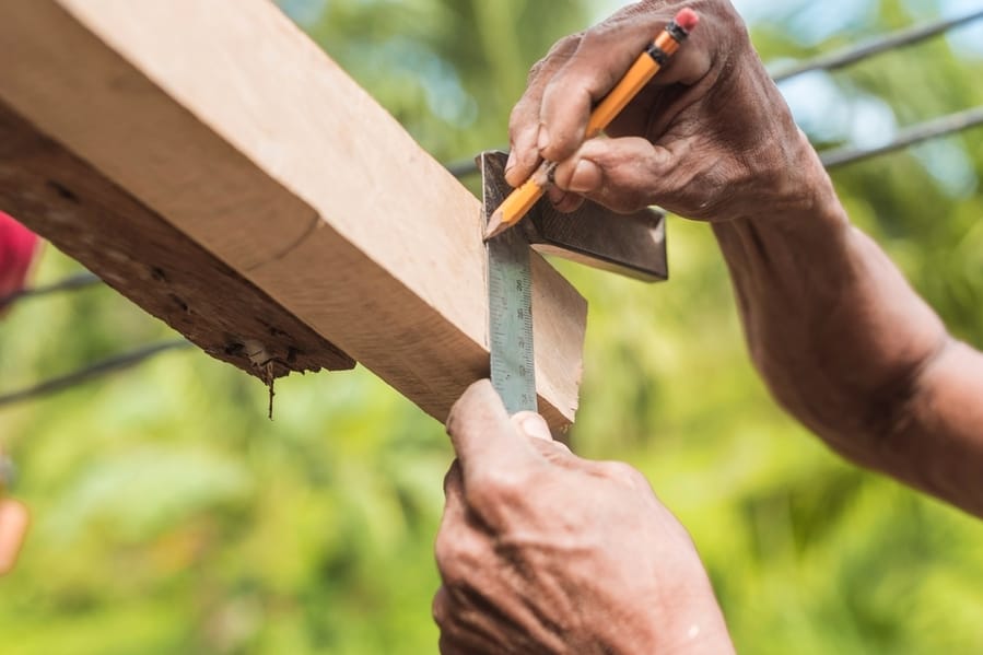 A Carpenter Marks The Excess Edge Of A Wood Rafter With A Pencil