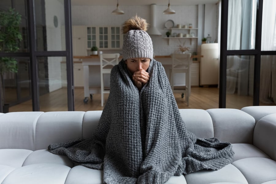 Female Sitting On Couch At Freezing Cooled Studio Flat