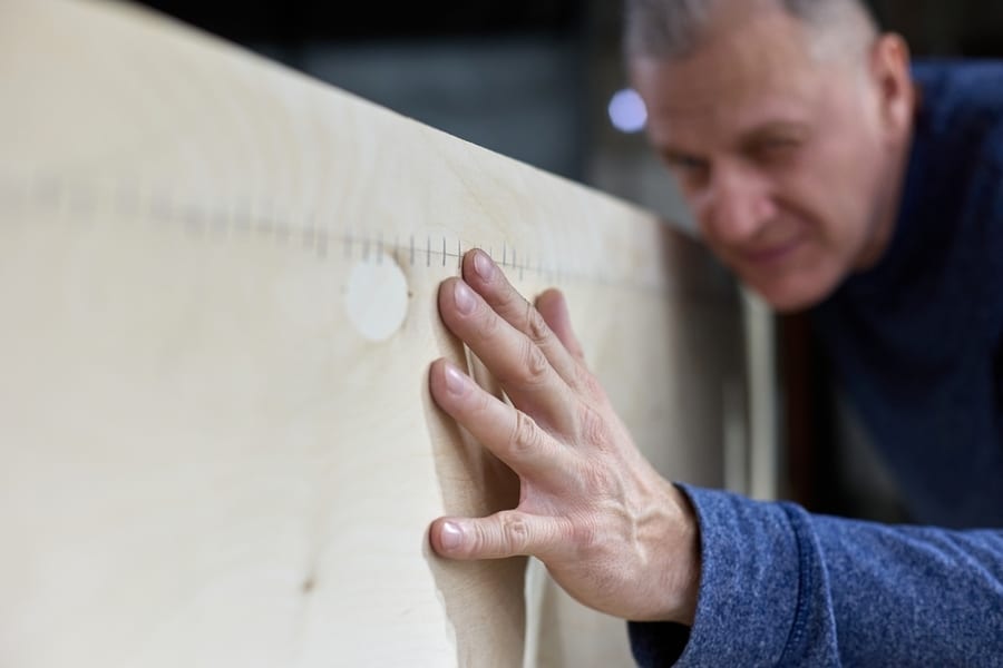 Mature Carpenter Checks The Quality Of The Plywood Frame