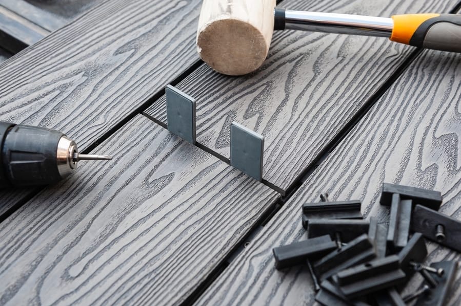 Screwdriver, Rubber Head Mallet And Black Plastic Fixings On A Grey Decking Boards