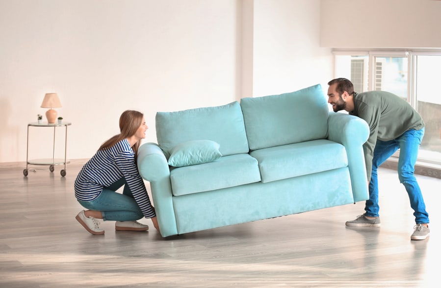 Young Couple Moving Sofa