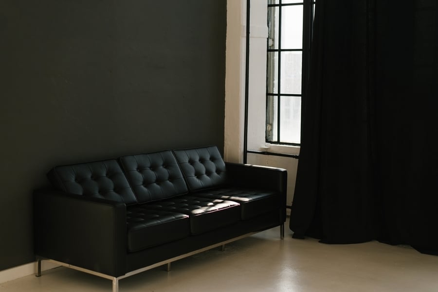 A Brutal Black Sofa In A Room With Dark Gray Walls And Black Curtains On The Window