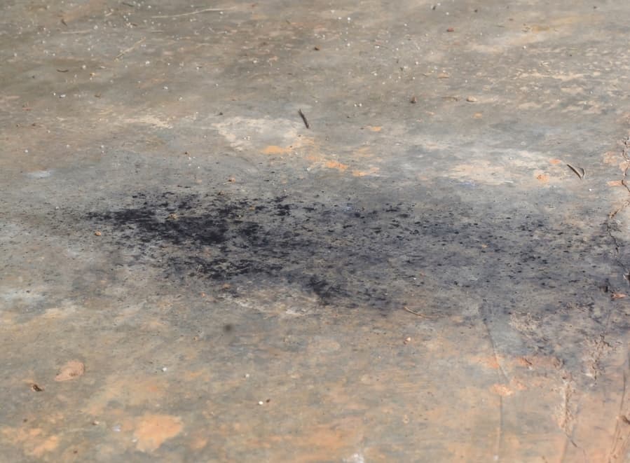 Black Soot Or Oil Slick From Car Exhaust Pipe Droped On Dirty Cement Or Concrete Floor In Old Garage