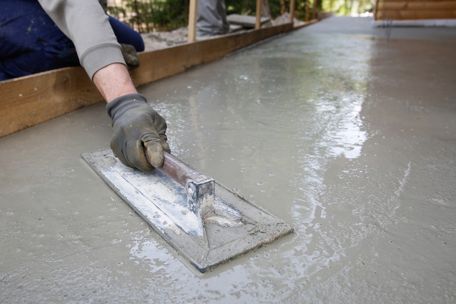 Mason Leveling And Screeding Concrete Floor Base With Square Trowel In Front Of The House