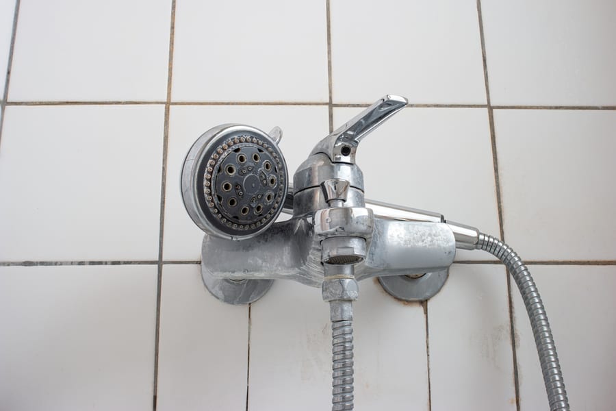 Old Dirty Limescale Chalk Covered Shower Head And Bathtub Faucet Close Up Low Angle View.