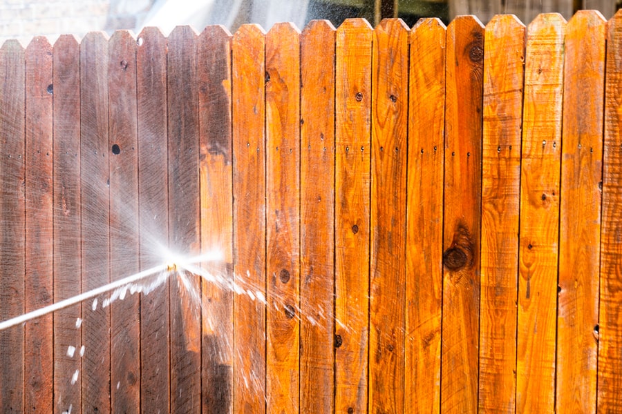 Stay At Home House Repairs , Pressure Washing Fence With A High Pressure Washer , Cleaning Old Dirty Planks Of Wood On Wooden Fence In Suburb Neighborhood