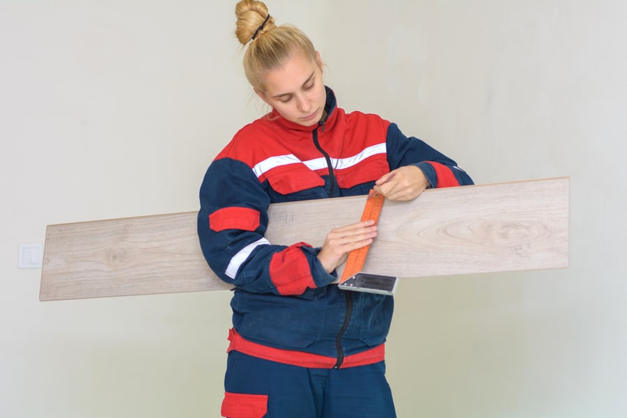Woman Measuring And Marking Laminate Floor Tile