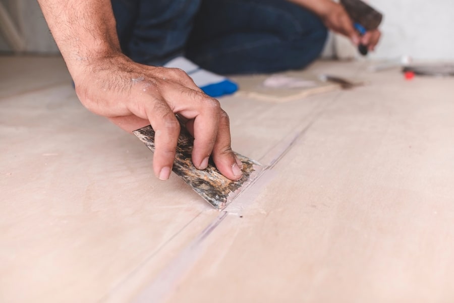 A Carpenter Filling Gaps In Wood Floors.