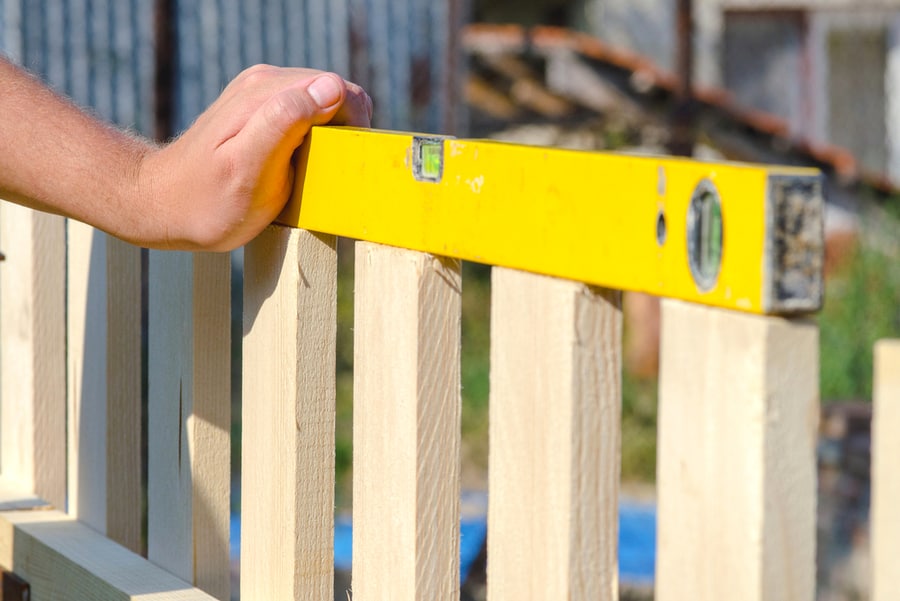 Man Checking Fence With Spirit Level