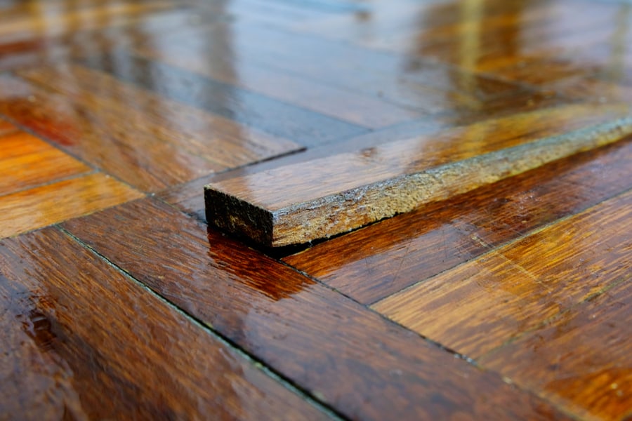 A Piece Of Parquet Floor Tile Slab Sticking Out After Being Stepped On As The Wooden Strip Has Become Unglued And Loose Due To Wear And Tear Over Time.