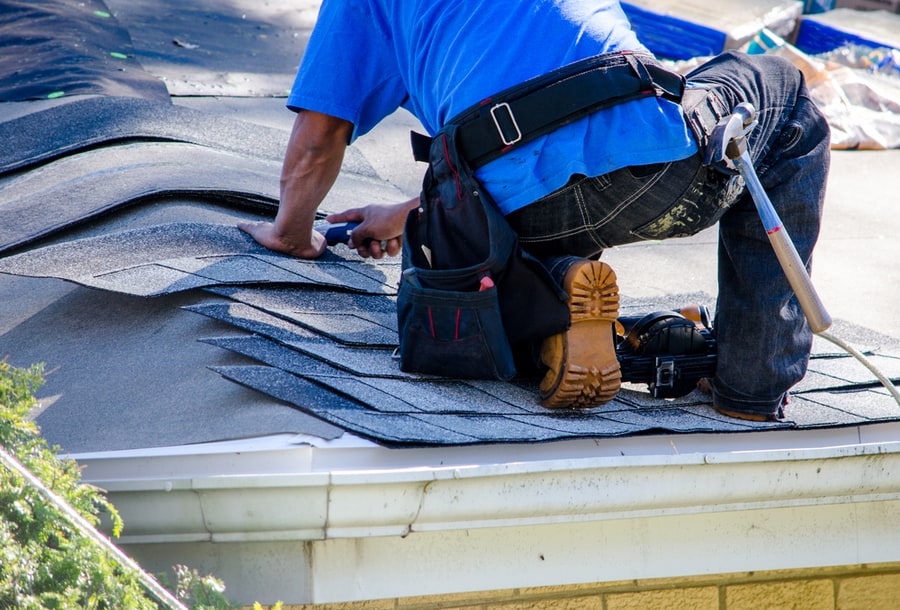 A Worker Replaces Shingles On The Roof