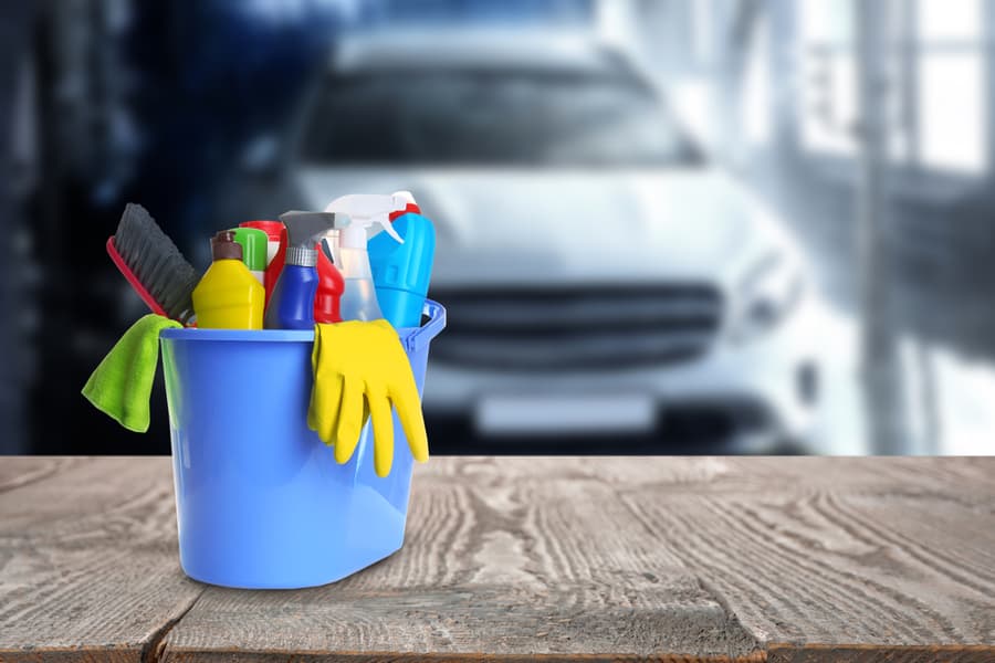 Bucket With Cleaning Supplies On Wooden Surface