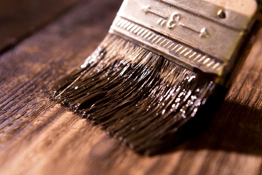 Male Hand Paint Wooden Surface With Brown Paint Using A Paintbrush