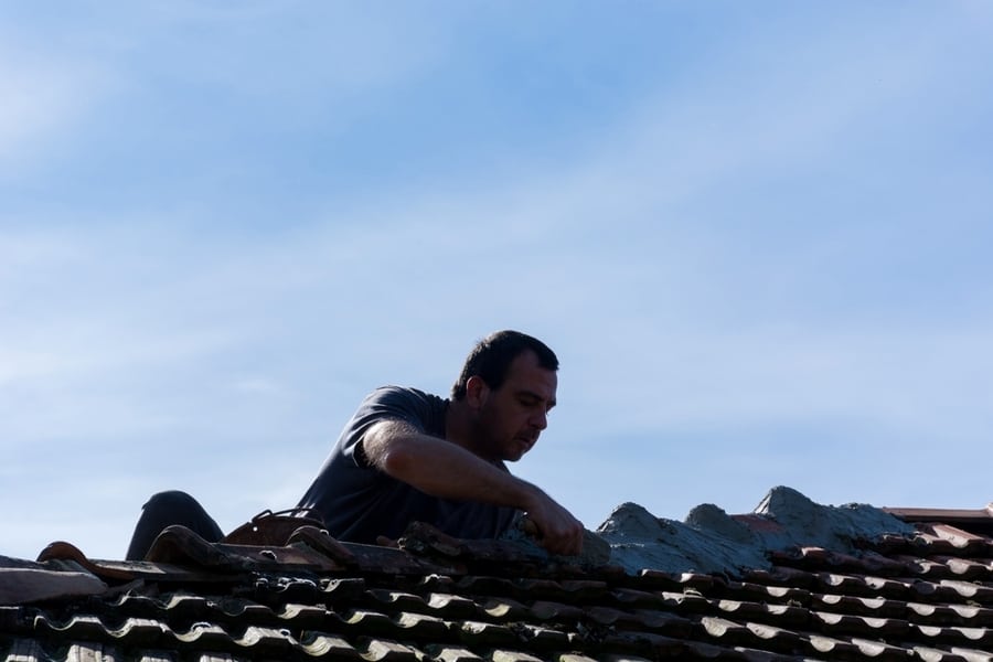 Man Reparing Roof Tiles With Cement