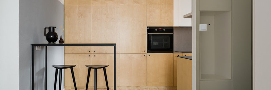 Panorama Of Modern Style Kitchen With Birch Plywood Cupboards And Black Table With Tall Bar Stools