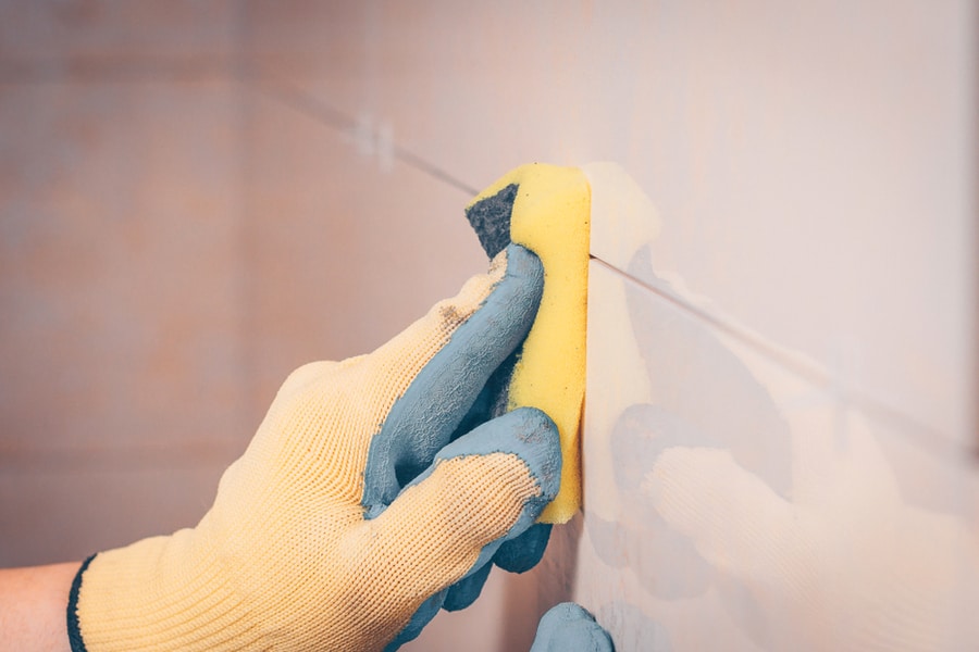 The Working Tiler Wipes The Tile On The Wall With A Damp Sponge