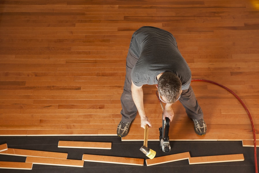 Top View Of A Man Installing Planks Of Hardwood Floor