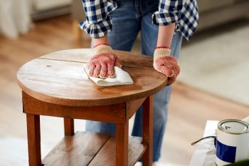 Woman Cleaning Old Round Wooden Table Surface With Paper Tissue